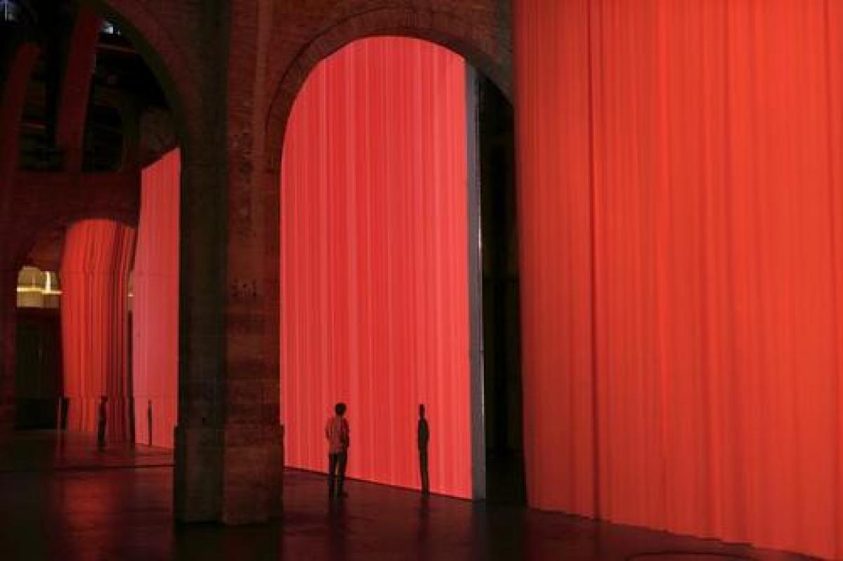 La silhouette d'un homme devant un immense rideau rouge fixé devant des arches monumentales en pierre