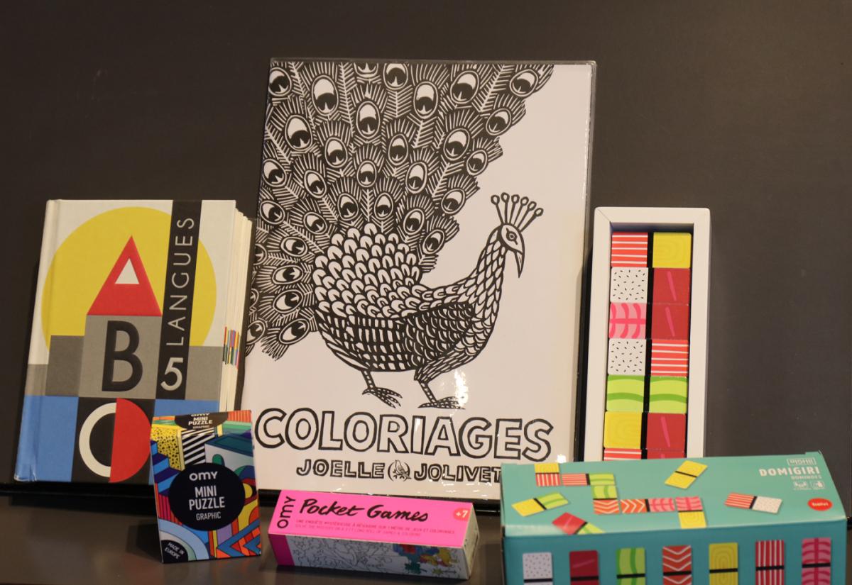 Sur table des jeux et des livres colorés pour enfants et un album de coloriage noir et blanc avec un dessin de faisan